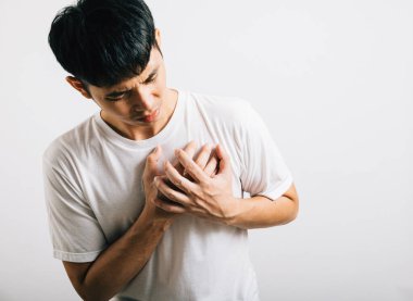 Kollarını göğsüne dolayan Asyalı genç adam kalp krizi stüdyosunun izole ettiği beyaz arka plan, mutlu yaşam tarzı erkeklerin göğüs ağrısı kalp rahatsızlığı sorunları yüzünden acı çekiyor.