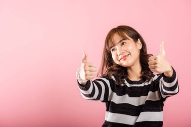 Pembe arka planda genç bir Asyalı kadının portresi, gülümseyen ve onay işareti veren, anlaşma ve başarıyı ifade eden. Pozitif tavrı gerçekten bulaşıcı..