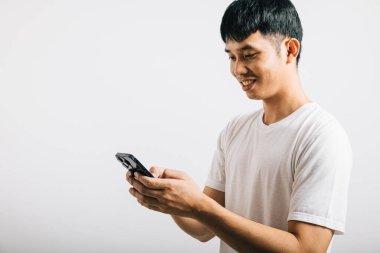 Sosyal medya stüdyosu için cep telefonu kullanan Asyalı gülümseyen genç adam, izole edilmiş beyaz arka plan, akıllı telefondan mesaj yazan mutlu yaşam tarzı erkekler, online mobil uygulama