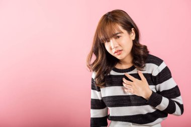 Göğüs ağrısına baskı yapan genç bir kadın pembe arka planda izole edilmiş acı dolu bir ifade kalp ağrısı, kalp krizi geçiren bir kadın, ağrılı kramplar.