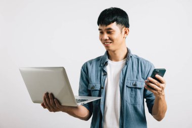 Portre Asyalı gülümseyen genç adam dizüstü bilgisayar ve cep telefonu stüdyosu izole edilmiş beyaz arka plan, Happy heyecanlı iş adamı bilgisayar ve akıllı telefon, modern teknoloji ve önem kullanıyor.