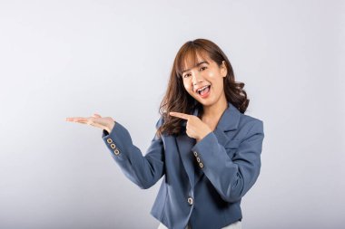 Asya Tayland mutlu portresi güzel genç bir iş kadını avucunun içinde bir şeyi tutmak için ayakta duruyor ve işaret ediyor, stüdyo resmi beyaz arka planda izole edilmiş, fotokopi alanı ile.