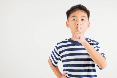 Genç çocuk dudaklarını parmaklıyor sessiz sessiz jest, mutlu Asyalı çocuk sessiz kalmak için sessizliği işaretliyor, sessiz stüdyo çekimi beyaz arka planda izole edilmiş, kopyalama alanı ile.