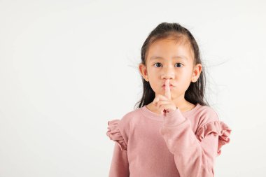 Genç kız dudaklarını parmaklıyor sessiz jest yapıyor, Mutlu Asyalı anaokulu çocuğu sessiz kalmak için sessizliği işaretliyor, sessiz stüdyo çekimi beyaz arka planda izole edilmiş, fotokopi alanı ile.
