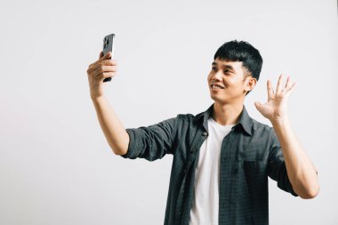 Akıllı telefondan çekilen Asyalı bir adamın özçekim anı, beyaz bir stüdyoda gülümsemesini ve heyecanını yakalıyor. Kendini ifade etmek ve mutlu selamlar