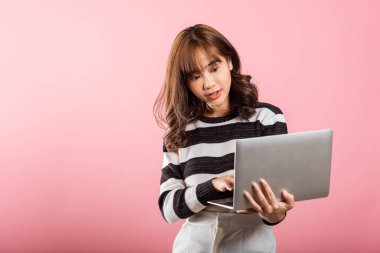 Mutlu Asyalı güzel bir kadının portresi dizüstü bilgisayarla gülümseyen bir yüz tutuyor kameraya bakıyor, pembe arka planda izole edilmiş bir stüdyo fotoğrafı, fotokopi odası, dizüstü bilgisayar.
