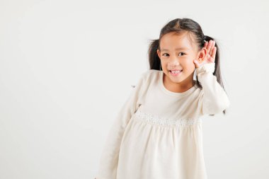 Asyalı genç bir çocuğun portresi, kulak misafiri olurken gülümsemesi kulak misafiri oluyor. Kulak üstüne kulak çekimleri, beyaz arka planda izole edilmiş fotokopi odası işitme hareketi, anaokulu kızı.