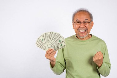 Asyalı gülümseyen yaşlı adamın elinde beyaz arka planda çekilmiş bir deste para banknotları var. Mutlu yaşlı pozitif heyecan dolar banknotları fanatiği, mali başarı