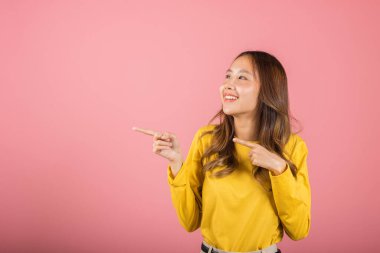 Asyalı güzel bir kadın gülümsüyor. Parmak ucunda pembe arka planda duruyor. Taylandlı mutlu bir kadın yüzü.