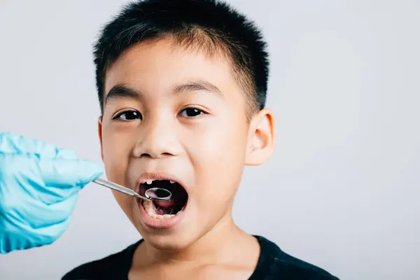 stock image In a pediatric dentists office a doctor examines a childs mouth post removal of a loose milk tooth. Dental instruments assist in examination. Doctor uses mouth mirror to checking teeth cavity