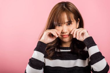 Hüzünlü, mutsuz, mutsuz, ağlayan, üzgün, umutsuz, pembe arka planda izole edilmiş stüdyo çekimleri, Asyalı, güzel, genç bir kadın kötü ruh hali, gözyaşlarını parmaklarıyla silme, negatif duygu.