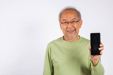 Asyalı gülümseyen, cep telefonlu, boş bir ekranlı stüdyo resmi olan, beyaz arka planda izole edilmiş, cep telefonu görüntüsü gösteren mutlu, yaşlı bir adam, App reklamı.