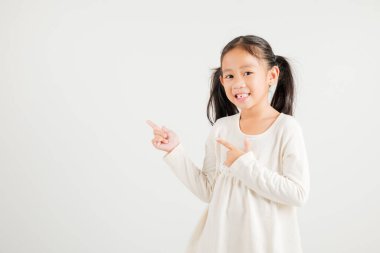 Mutlu Asya portresi gülümseyen küçük kız parmak boşluğunu gösteriyor, stüdyo resmi beyaz arka planda izole edilmiş, Tayland anaokulu çocuğu kopya alanı ile işaret ediyor.