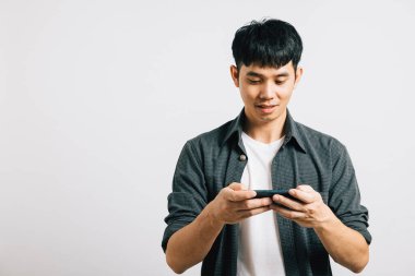 Portre Asyalı gülümseyen genç adam cep telefonuyla stüdyoda izole edilmiş beyaz arka plan, mutlu yaşam tarzı işadamı internet, mutluluk ve keyif kullanarak oyun oynuyor.