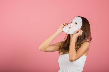 Yüzüne kozmetik kâğıt maske takan Asyalı genç bir kadın. Stüdyo resmi. Pembe arka planda izole edilmiş, doğal makyaj maskeli güzel bir kadın.