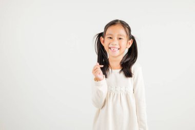 Mutlu bir Asyalı genç kızın portresi, özgüvenle gülümseyen, beyaz arka planda izole edilmiş parmak stüdyosu çekimleri ile küçük kalp işaretini gösteren. Anaokulu çocuğu Sevgililer Günü için sevgi ve neşe ifade ediyor.