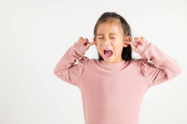 Asyalı genç bir kızın acı ve hayal kırıklığının ifadesi, kulakları kapatırken ve stüdyodaki gürültüden kaçmak için parmaklarıyla gözlerini kapatırken izole edilmiş beyaz arka plan, anaokulu çocuğu