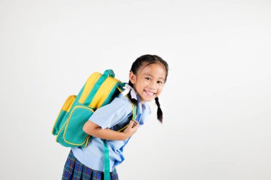 Portre gülüşü Asyalı küçük kız anaokulu elinde yeşil ve sarı bir sırt çantasıyla stüdyo poz veriyor izole edilmiş beyaz arka plan, mutlu tatlı kadın okul üniformalı ekose etek giyiyor, okula geri dönüyor.