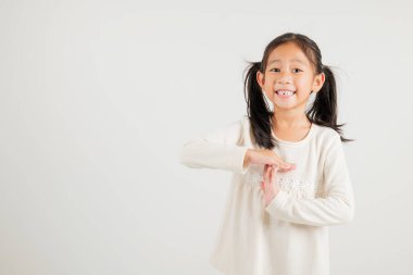 Yakından bakınca gülümseyen genç kız el hareketi yapıyor. Stüdyo çekimleri beyaz arka planda. Anaokulu çocuğu el işaretini kırıyor, zamanı fotokopi ile durduruyor.