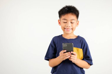 Beyaz arka planda izole edilmiş akıllı cep telefonu stüdyosu çekimleri ile heyecanla gülümseyen yakışıklı çocuk, Taylandlı çocuk akıllı telefondan mesajları okurken şaşırdı.