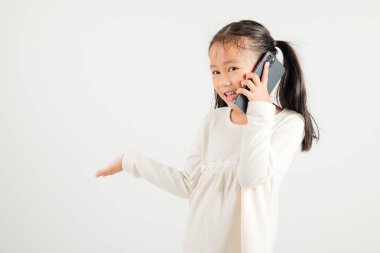 Mutlu Asyalı genç kız gülümsemesi heyecanlı konuşan akıllı cep telefonu stüdyosu beyaz arka planda izole edilmiş Tayland anaokulu çocuğu akıllı telefondan jest yapıyor.