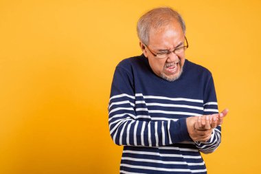 Asyalı gözlüklü yaşlı bir portre. Acı dolu stüdyo çekimini tutuyor. Sarı arka plan izole edilmiş.