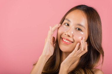 Kadınlık. Asyalı güzel, genç bir kadın gülümseyen kozmetik bantlar gözlerinin altına jel, portre kadın temiz cilde dokunuyor yüzüne tıbbi hidrojel göz bandı, pembe arka planda izole edilmiş, cilt bakımı.