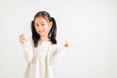 Mutlu bir Asyalı genç kızın portresi, özgüvenle gülümseyen, beyaz arka planda izole edilmiş parmak stüdyosu çekimleri ile küçük kalp işaretini gösteren. Anaokulu çocuğu Sevgililer Günü için sevgi ve neşe ifade ediyor.