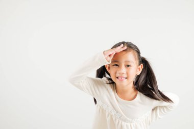 Araştırma konsepti. Uzaklara bakan Asyalı genç bir kız, beyaz arka planda izole edilmiş bir şekilde çekilen bir stüdyo fotoğrafı, gözleriyle mesafeye bakan mutlu anaokulu çocuğunun portresi.