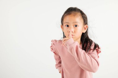 Genç kız dudaklarını parmaklıyor sessiz jest yapıyor, Mutlu Asyalı anaokulu çocuğu sessiz kalmak için sessizliği işaretliyor, sessiz stüdyo çekimi beyaz arka planda izole edilmiş, fotokopi alanı ile.