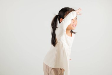 Araştırma konsepti. Uzaklara bakan Asyalı genç bir kız, beyaz arka planda izole edilmiş bir şekilde çekilen bir stüdyo fotoğrafı, gözleriyle mesafeye bakan mutlu anaokulu çocuğunun portresi.