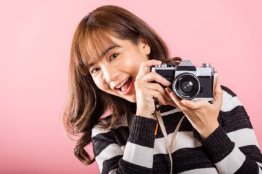 Çekici, enerjik, mutlu bir Asyalı portresi güzel, gülümseyen genç bir kadın fotoğraf çekiyor ve geçmişe dönük fotoğraf makinesine bakıyor pembe arka planda izole edilmiş bir şekilde çekmeye hazır.