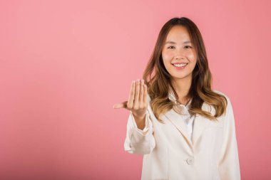 Mutlu bir Asyalı portresi güzel tatlı bir genç kadın gülümsüyor. Dostane bir şekilde el ele tutuşup fotoğraf stüdyosuna davet ediliyor. Pembe arka planda, fotokopi alanı ile izole edilmiş.