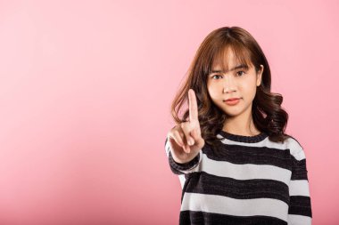 Asyalı kendine güvenen genç bir kadının pembe arka planda kısa bir süre izole edilmiş bir jest stüdyosu için tek parmağını göstermesi, bir kadının onaylamaması gereken bir şeyi yasaklaması.
