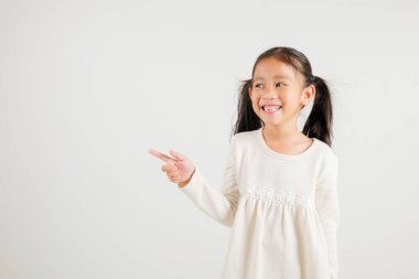 Mutlu Asya portresi gülümseyen küçük kız parmak boşluğunu gösteriyor, stüdyo resmi beyaz arka planda izole edilmiş, Tayland anaokulu çocuğu kopya alanı ile işaret ediyor.