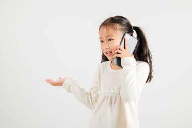Mutlu Asyalı genç kız gülümsemesi heyecanlı konuşan akıllı cep telefonu stüdyosu beyaz arka planda izole edilmiş Tayland anaokulu çocuğu akıllı telefondan jest yapıyor.