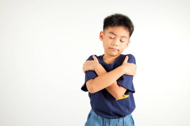 Mutlu, gülümseyen, kendine sarılan Asyalı çocuk beyaz arka plan, özgüven ve özgüven konsepti ile izole edilmiş kısa bir stüdyoyu hatırla.