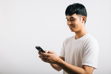 Sosyal medya stüdyosu için cep telefonu kullanan Asyalı gülümseyen genç adam, izole edilmiş beyaz arka plan, akıllı telefondan mesaj yazan mutlu yaşam tarzı erkekler, online mobil uygulama