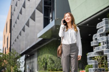 Beautiful young Asian woman calling and talks on telephone or mobile phone in city, Portrait of businesswoman smiling talking on mobile phone, people and technology communication concept