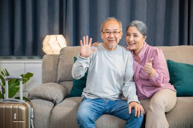 Mutlu Asyalı son sınıf çifti rahat bir koltukta otururken karşılıyor. Yaşlı adam ve kadın evdeki bir kanepede yan yana oturuyor.