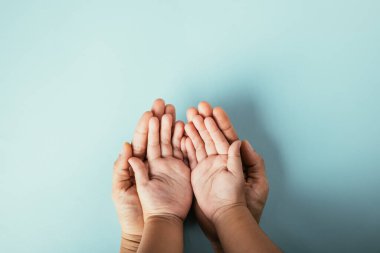 Soyutlanmış arka planda aile üst görünümü elleri var. Ebeveynler ve çocuklar, Aile ve Veliler Günü için destek ve sevgi ifade eden boş bir alan tutuyorlar..