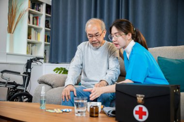 Steteskoplu beyaz üniformalı Asyalı hemşire, yaşlı bir adama tedavi dozajı ve sağlık sigortası konseptini açıklamakta yardım ediyor.