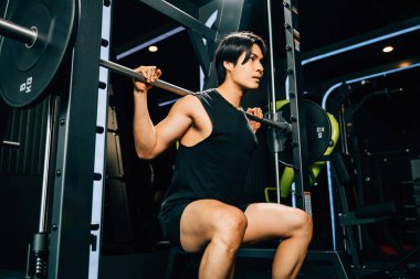 Asyalı kaslı adam spor yapıyor. Ağırlık çalışıyor. Spor salonunda halterle ağırlık çalışıyor. Erkek halter kaldırıyor.