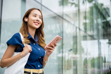 Kulaklıklı gülümseyen kız sanal sohbet uygulaması için cep telefonu kullanıyor ve sosyal medya videoları izliyor. Bu genç bir insanın mükemmel bir portresi..