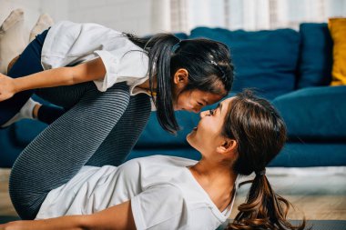 Bir anne çocuğunu bir aile formundayken tutarak kendini pilates yaparken uçak gibi uçarken hayal eder ve yoga rutinini güven uyumu ve mutluluğu teşvik eder..