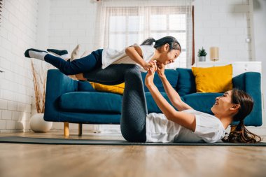 Bir anne ve kızı evde küçük kuş duruşuna odaklanarak eğlenceli bir yoga rutinini paylaşıyorlar. Gülüşleri güven ve denge dolu uyumlu ve neşeli bir aile anını yansıtıyor..