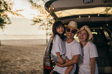 Asyalı bir aile gün batımında arabalarıyla sahilde oturuyor. Tatillerde ve tatillerde kendilerini tuhaf hissediyorlar. Baba, anne-kız iyi hafta sonları tatilleri. Plajda iyi eğlenceler. Yaz tatili kamp gezisi