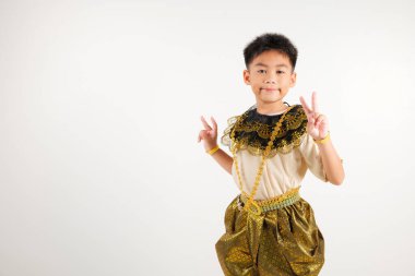 Taylandlı çocuk gülümseyen geleneksel Tayland elbisesi giysisi zafer ve barış işaretleri oluşturarak pozitiflik saçıyor. Stüdyo çekimi izole edilmiş beyaz arka plan, V işareti parmağı.
