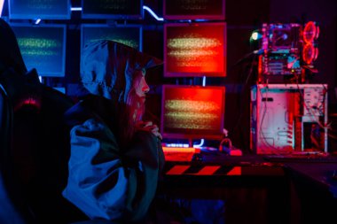 Kadın hacker kaput takıyor klavye ışığı altında sunuculara yazı yazıyor, oyun oynayan kadın karanlık oda, kadın hacker veri merkezine giriyor, Blockchain siber saldırısı