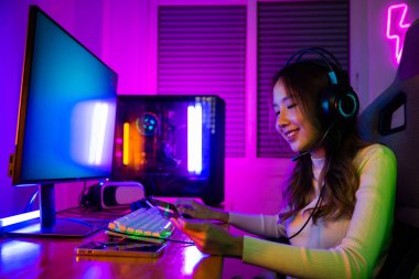 Kulaklık takan mutlu genç Asyalı kadın oyuncu. Maaş sonrası kart hesabı tutarak gülümsüyor. Kredi kartı kullanarak para harcayan bir kadın.